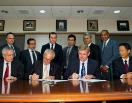 Photo of officials from both universities signing documents.