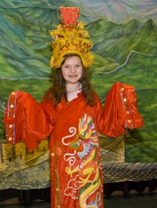 Photo of young girl wearing a decroative robe with a dragon on it.