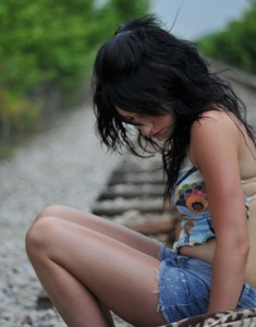 Photo of a girl sitting on a railroad track.