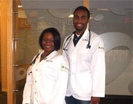 Photo of two students in lab coats.