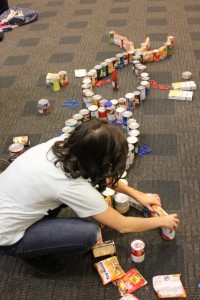 Photo of student making a sculpture out of canned goods.