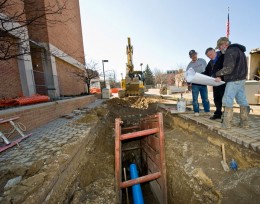 Photo of construction workers laying a blue pipe in the ground.