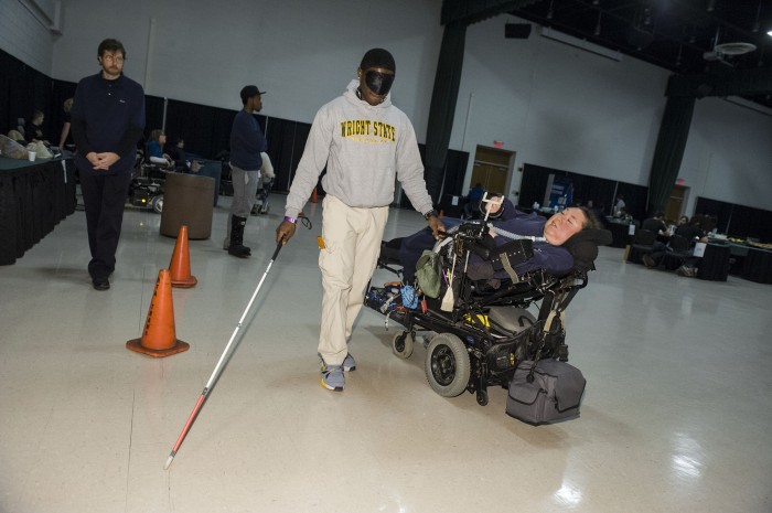 Photo of an able-bodied student walking blindfolded with a blind person's walking stick.