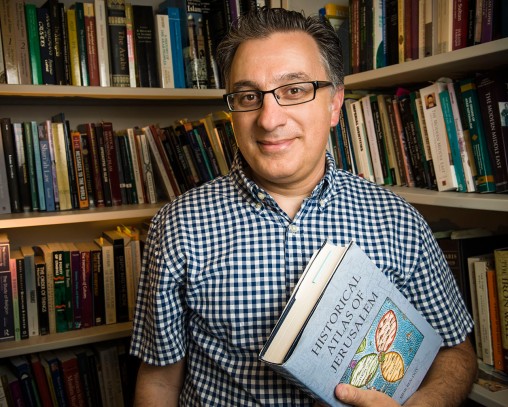 Awad Halabi in front of bookshelf