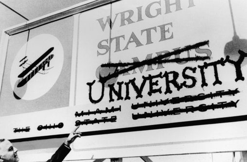 Brage Golding, Wright State's first president, pointing at the former Wright State Campus sign.