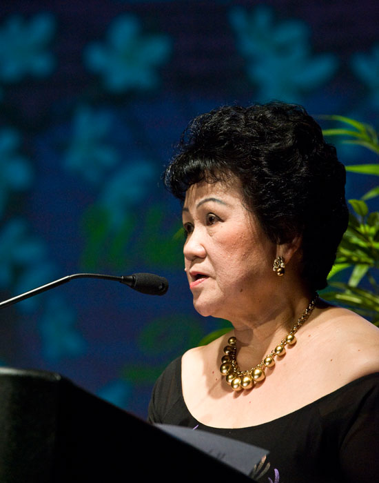 Photo of Mai Nguyen at a podium with flowers in the background.