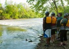 Photo os students and instructors standing on the shore observing mild white water during Wright State University's Introduction to Kayaking class.