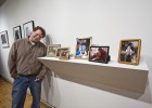Photo of artist Brad Cowie next to his work, several framed photographs.
