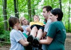 Photo of Wright State students and little sibs lifting another little sib over a string line in the Wright State woods.