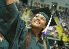 Photo of an undergraduate student waving to a family member in the crowd at graduation.