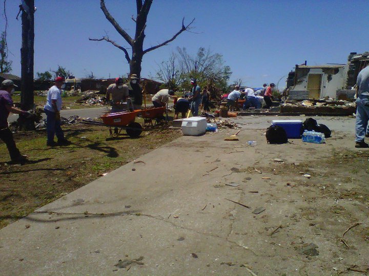 Photo of volunteers working to clean up the disaster site along a road.
