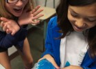 Photo of two girls squishing a bag with a blue gelatinous substance.