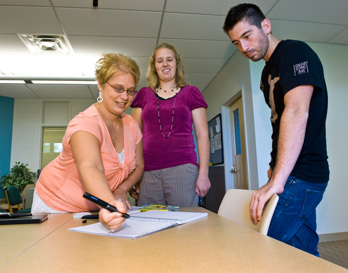 Photo of a female student demonstrating to two other students how to use a smartpen.