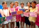 Photo of Campers showing off the cookbooks they created in “Kitchen Calculations” with recipes for hot chocolate and grape salad with a twist.
