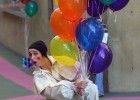 Photo of a student dressed as a clown hiding behind a bunch of balloons.