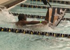 Photo of a male student in the pool with his cardboard boat.