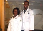 Photo of two students in lab coats.