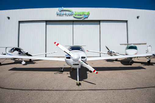 Three passenger planes parked in front of a building labeled "First Flight Aviation."