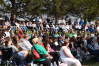 A crowd of people sit in lawn chairs at an outdoor event.