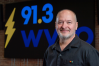 A man wearing a polo stands in front of a sign that reads "91.3 WYSO" with a lightning bolt.