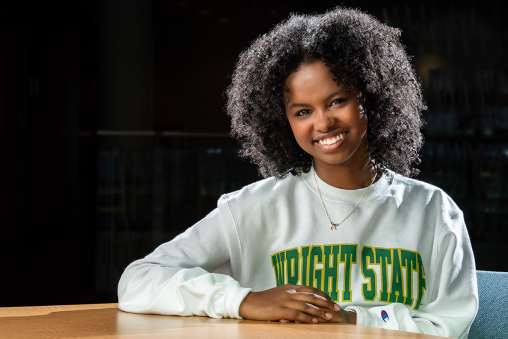 A person sitting at a table, wearing a sweatshirt with "WRIGHT STATE" across the front.