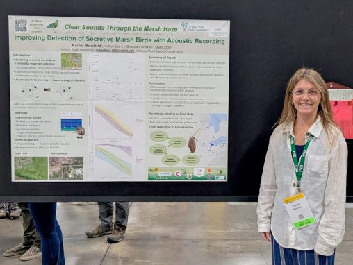 A woman stands in front of a poster at a research conference.