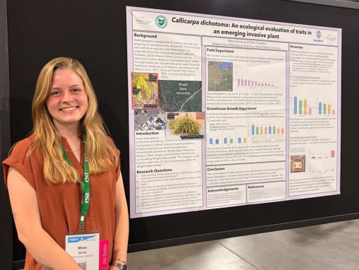 A woman stands in front of a poster at a research conference.