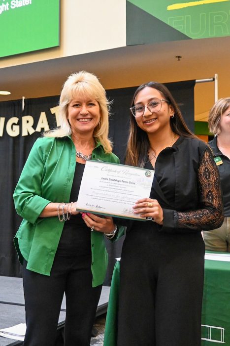 A student stands with the Dean of the College of Health, Education and Human Services, both holding a certificate.