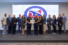 Several individuals in business attire and police officer uniforms standing together on a stage. The officers in the center are holding an award.