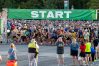 A large amount of runners stand under a "START" banner, preparing to begin a race.