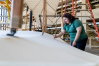 A woman in a Wright State shirt is dusting a life sized model of the Wright Flyer.