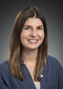 A woman in a button-up shirt posing for a professional portrait.