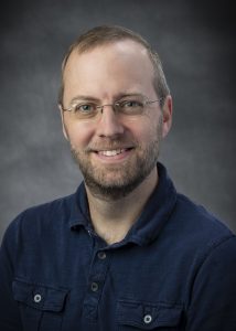 A man in a polo posing for a professional portrait.