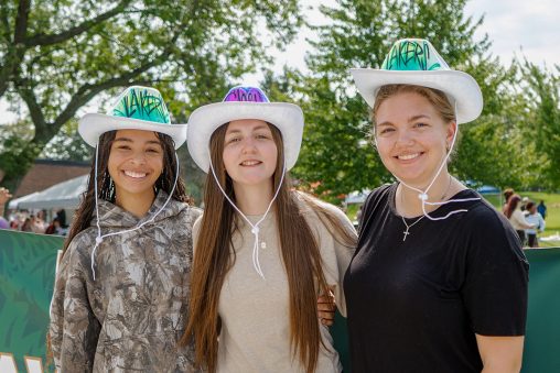 Three girls stand together wearing airbrushed cowboy hats that read "Lakers."