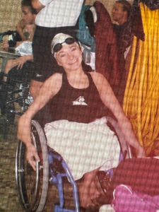A woman in a wheelchair wearing a Wright State Raiders swimsuit, swim cap and goggles.